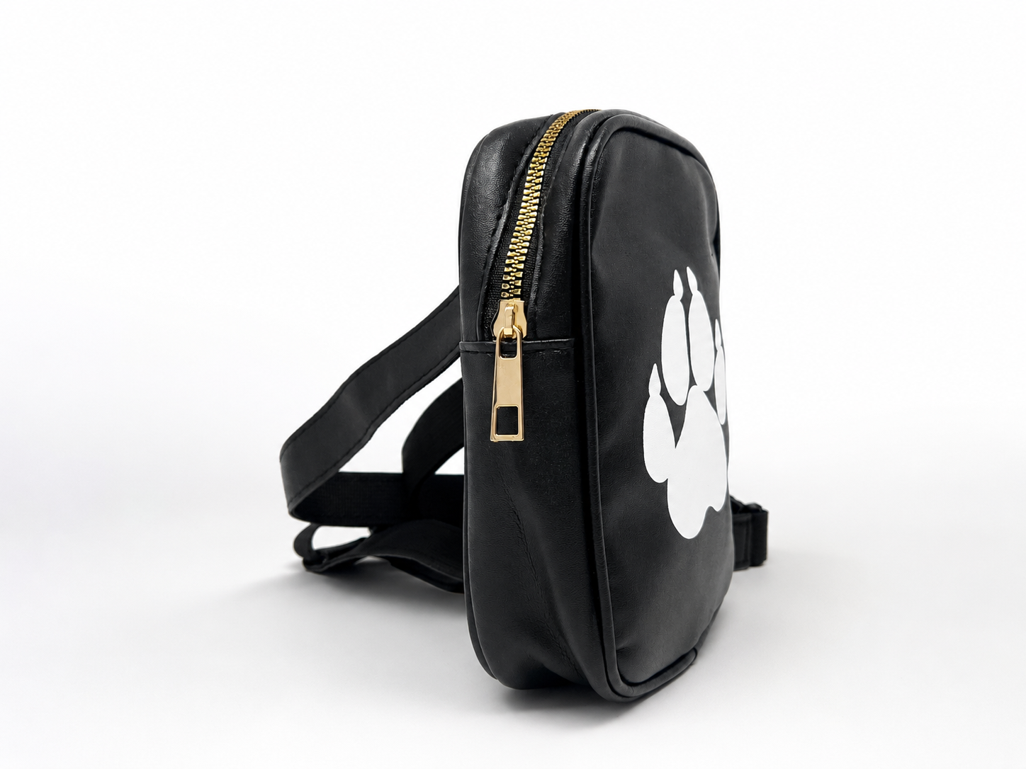 A black faux-leather crossbody bag with a gold zipper, a black strap, and a large white paw print graphic on the front, shown on a white background.